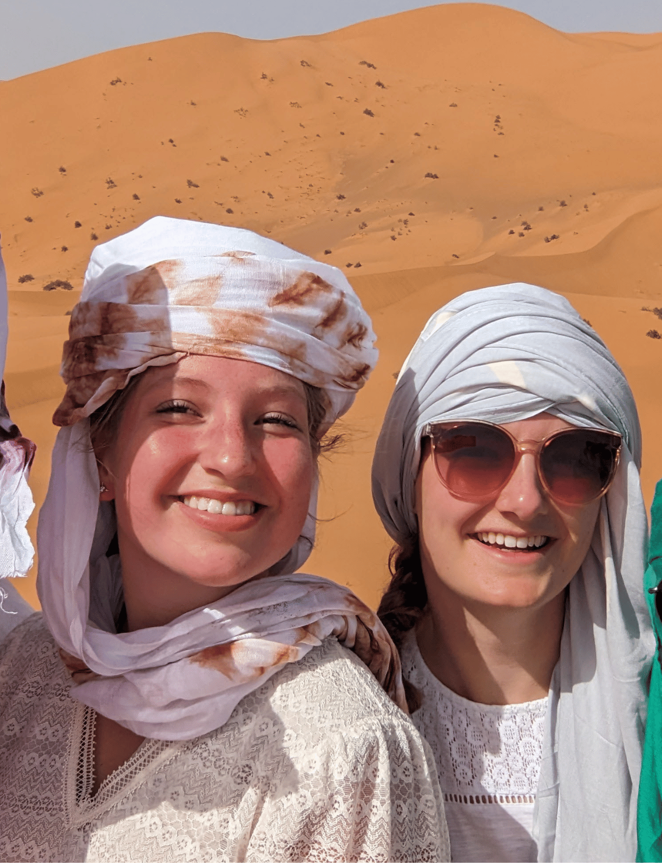 best cultural trip in morocco, two joyful travelers smiling in the vast Moroccan desert, embodying the spirit of adventure and cultural immersion on their journey.