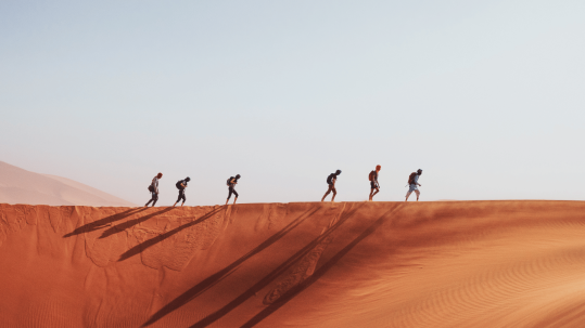 Adventurers traverse the undulating dunes in a desert expedition